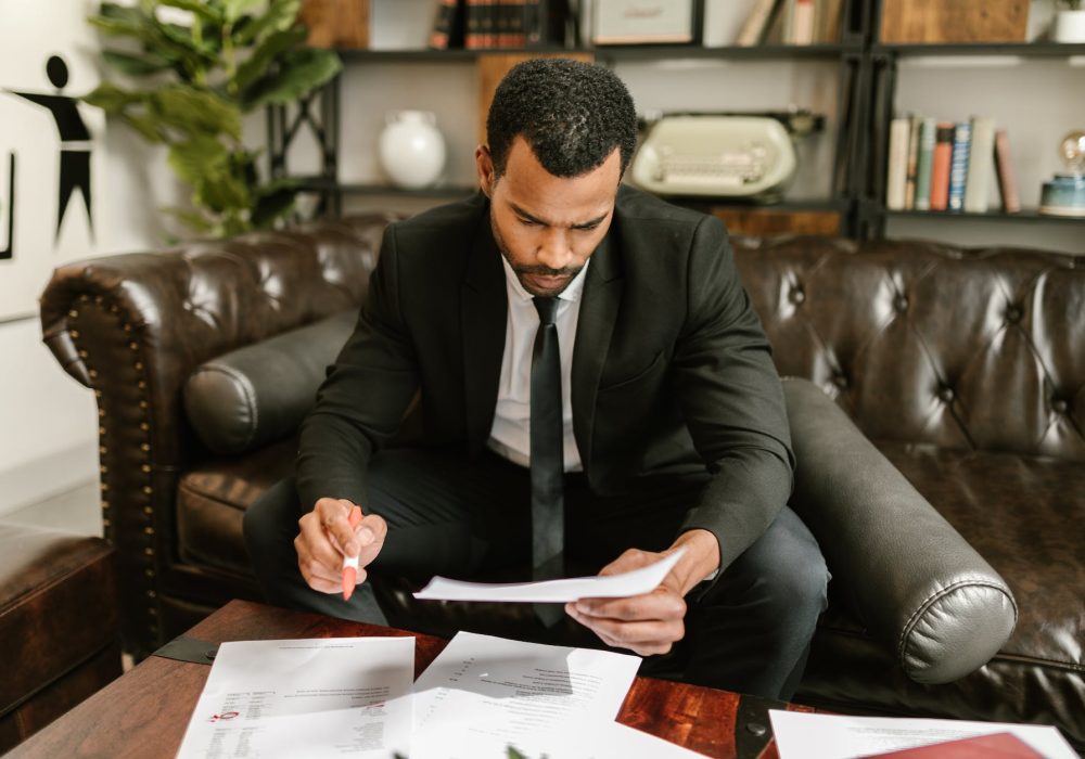 man sitting on brown leather sofa looking at documents